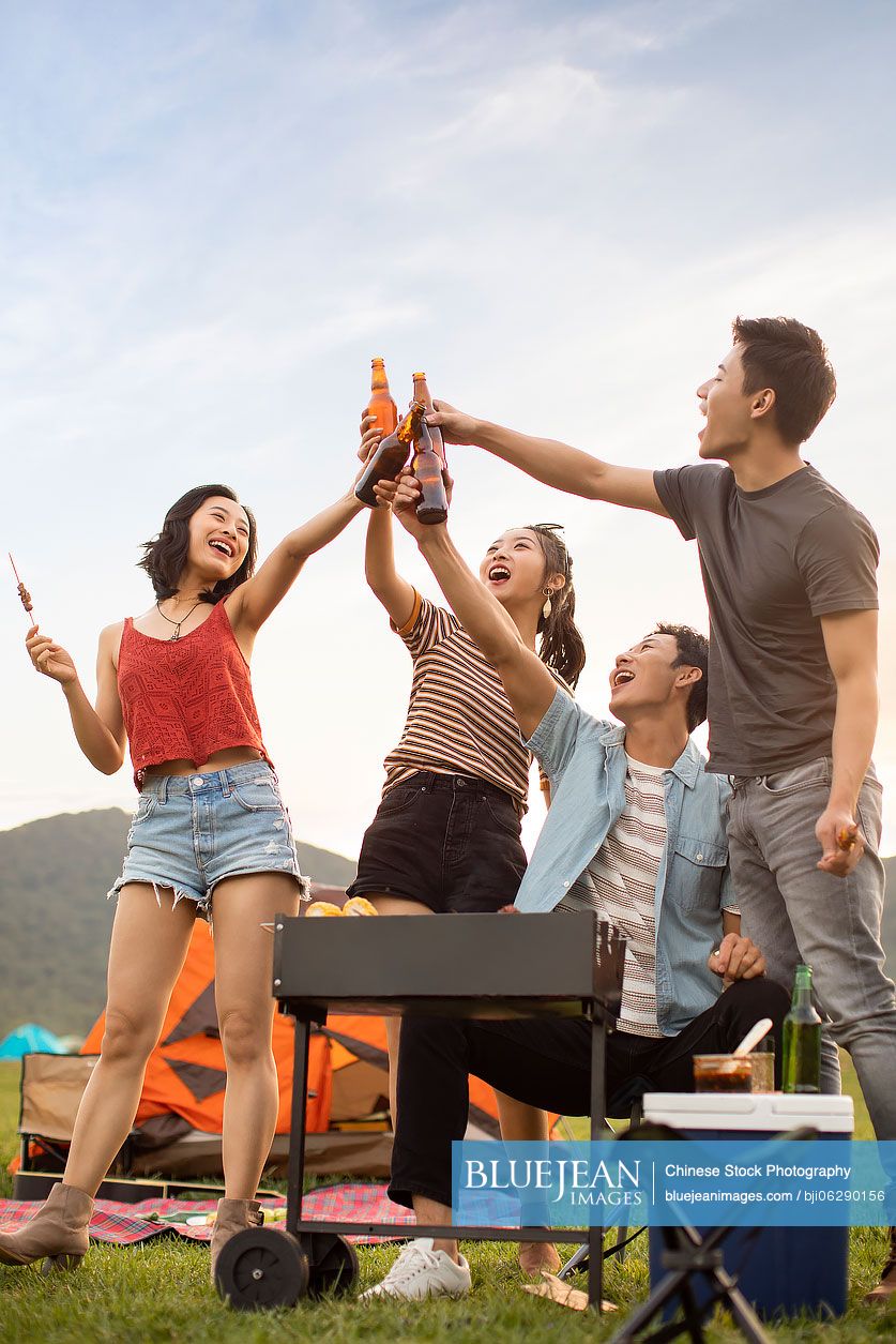 Happy young Chinese friends barbecuing outdoors