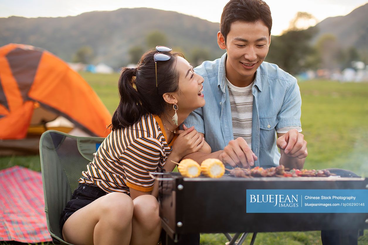 Happy young Chinese couple barbecuing outdoors