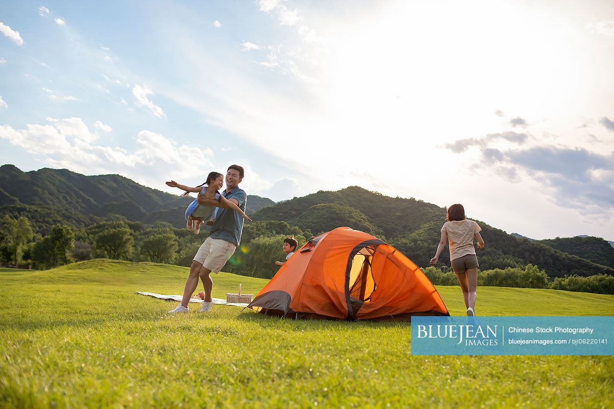 Happy young Chinese family camping outdoors