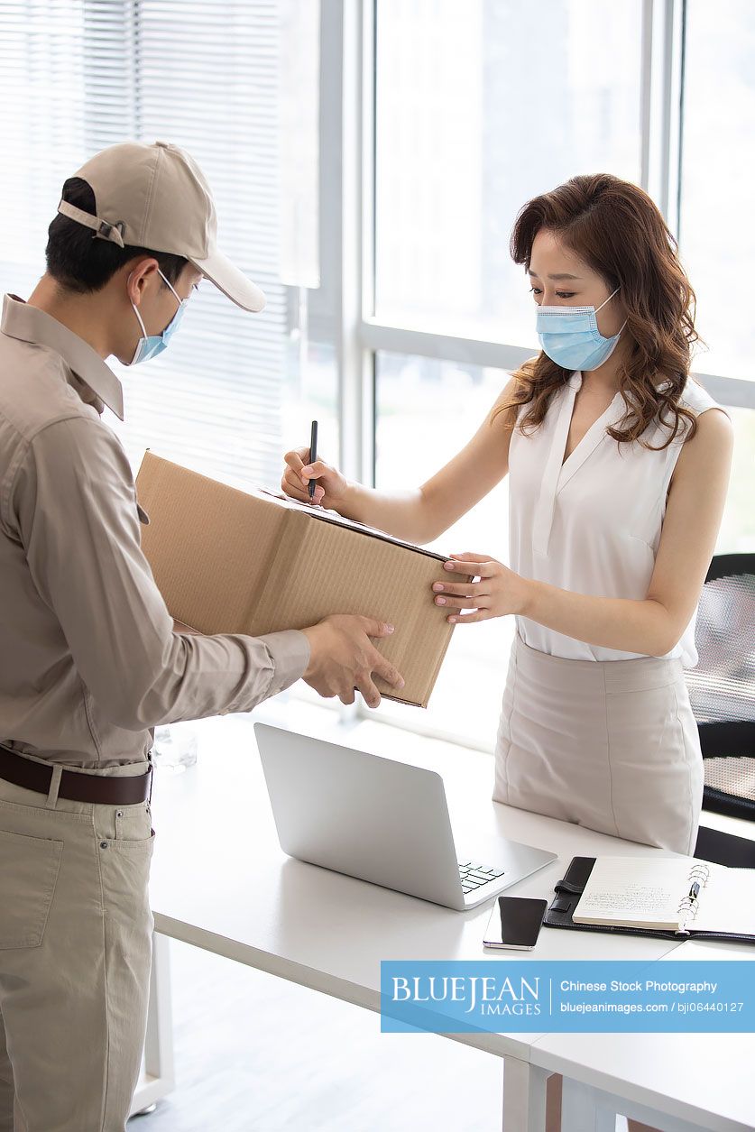 Young Chinese businesswoman signing for express delivery in office