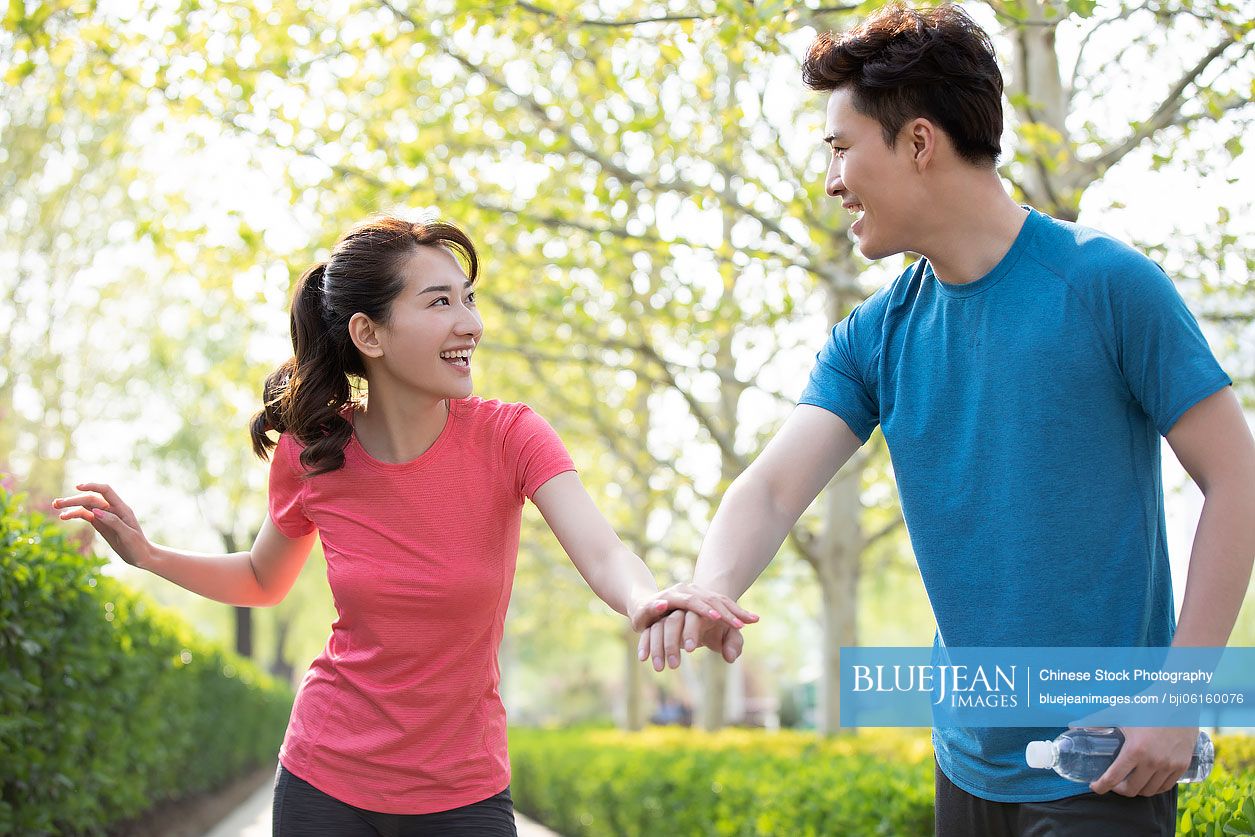 Happy young Chinese couple exercising in park