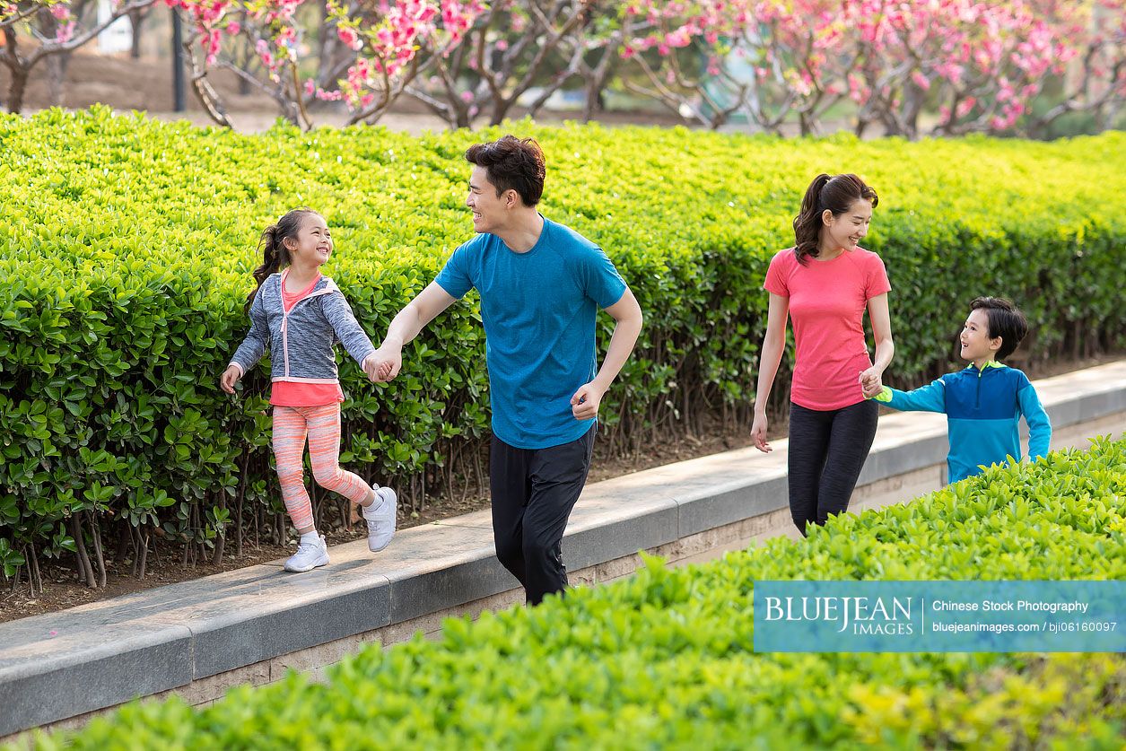 Happy young Chinese family playing in park