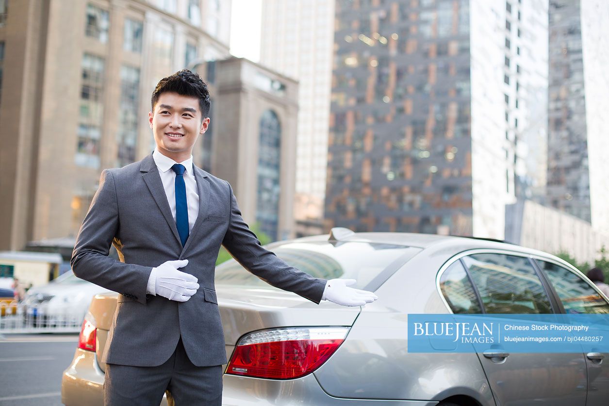 Chinese chauffeur greeting next to the car