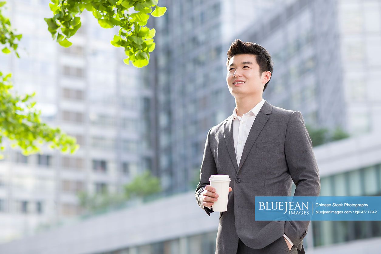 Young Chinese businessman with coffee cup