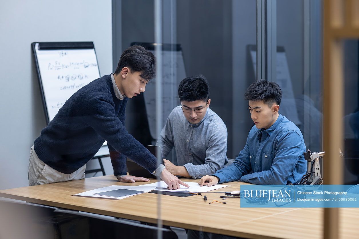 Confident Chinese designers checking a robotic arm