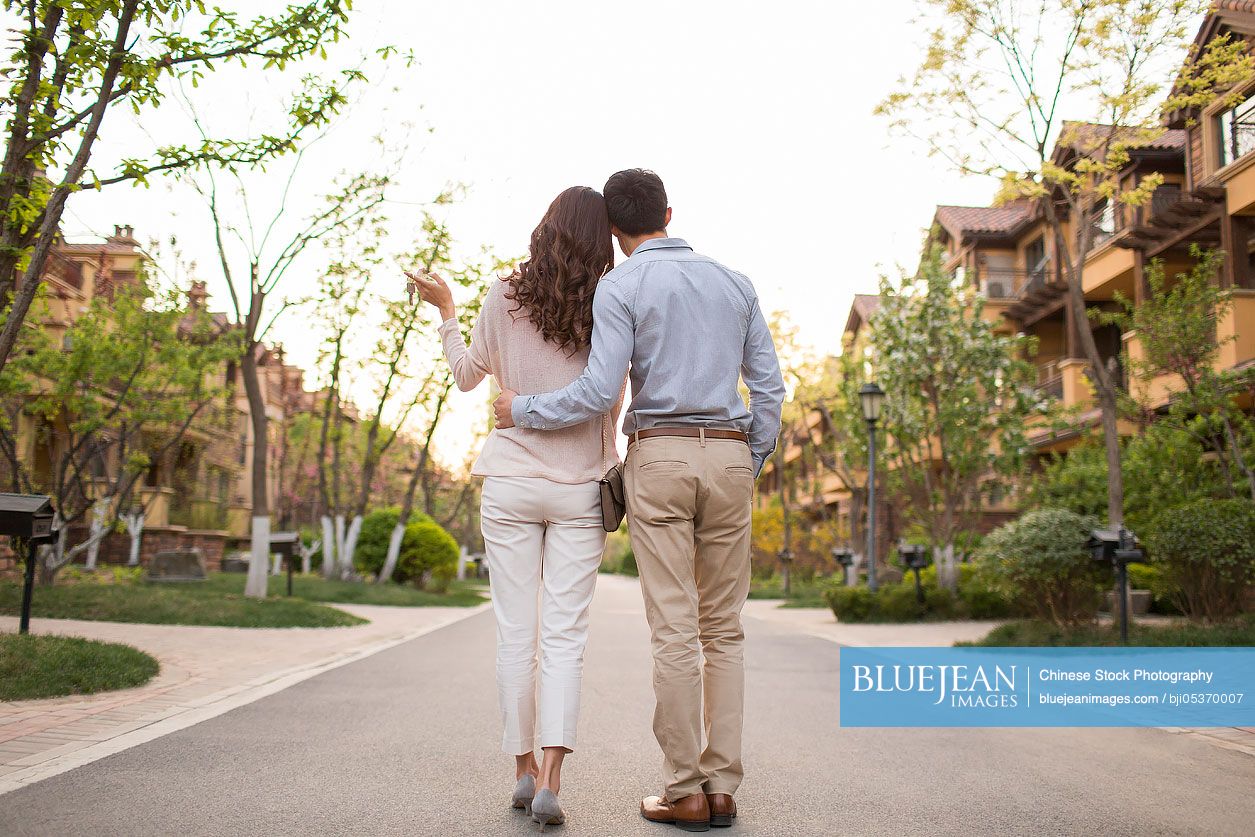 Rear view of happy young Chinese couple holding keys to new house