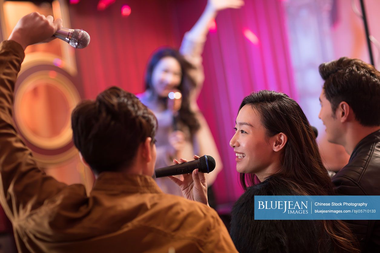Happy Chinese friends singing karaoke in nightclub