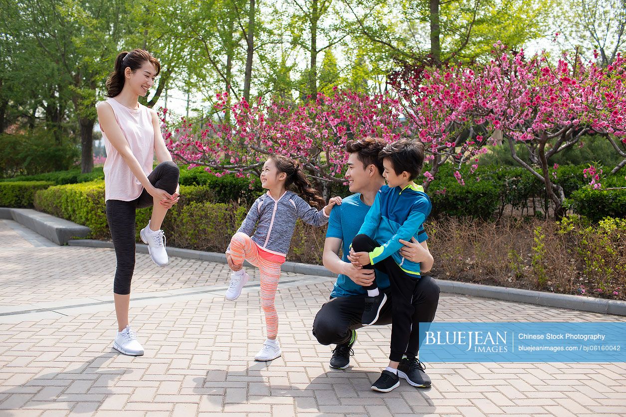 Happy young Chinese family exercising in park