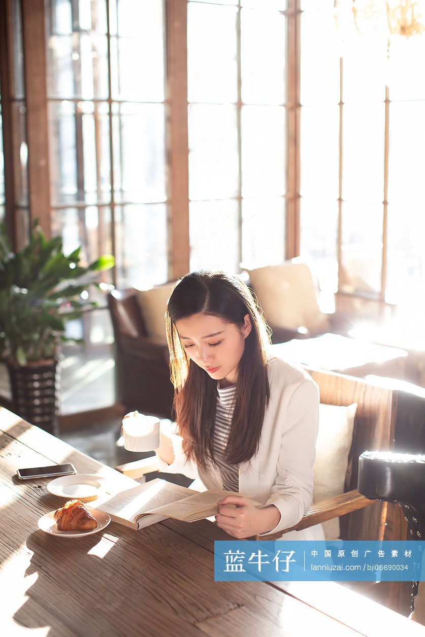 年轻商务女士在咖啡店看书