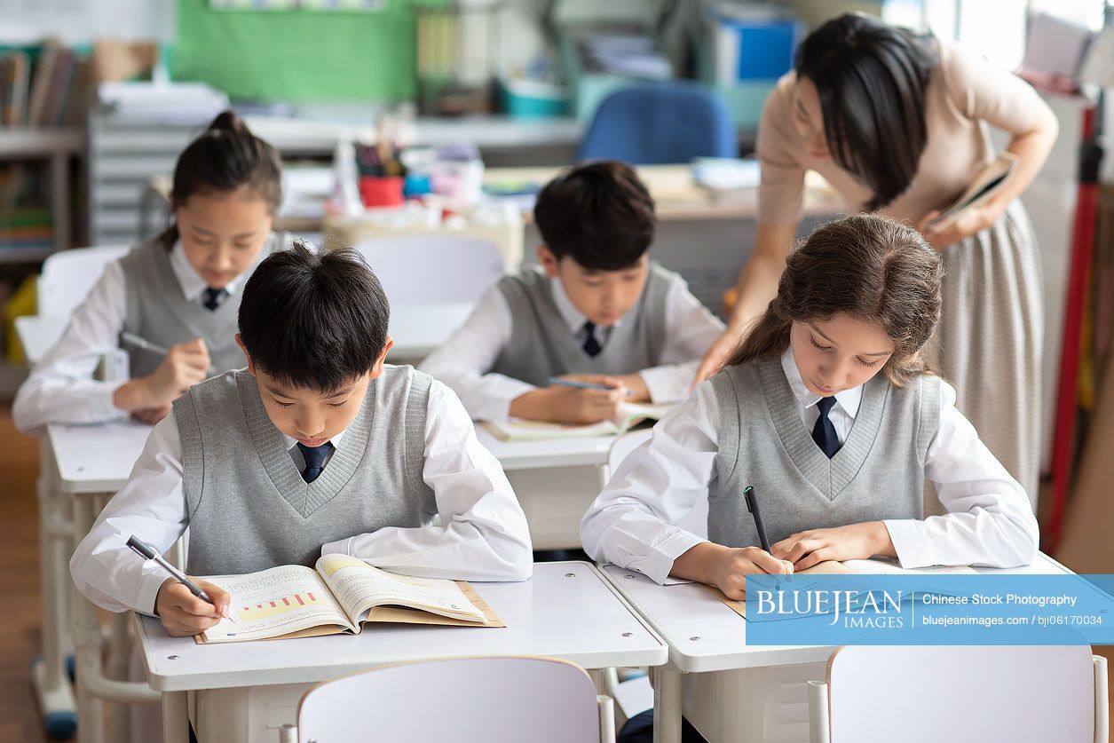 Young Chinese teacher helping students in classroom