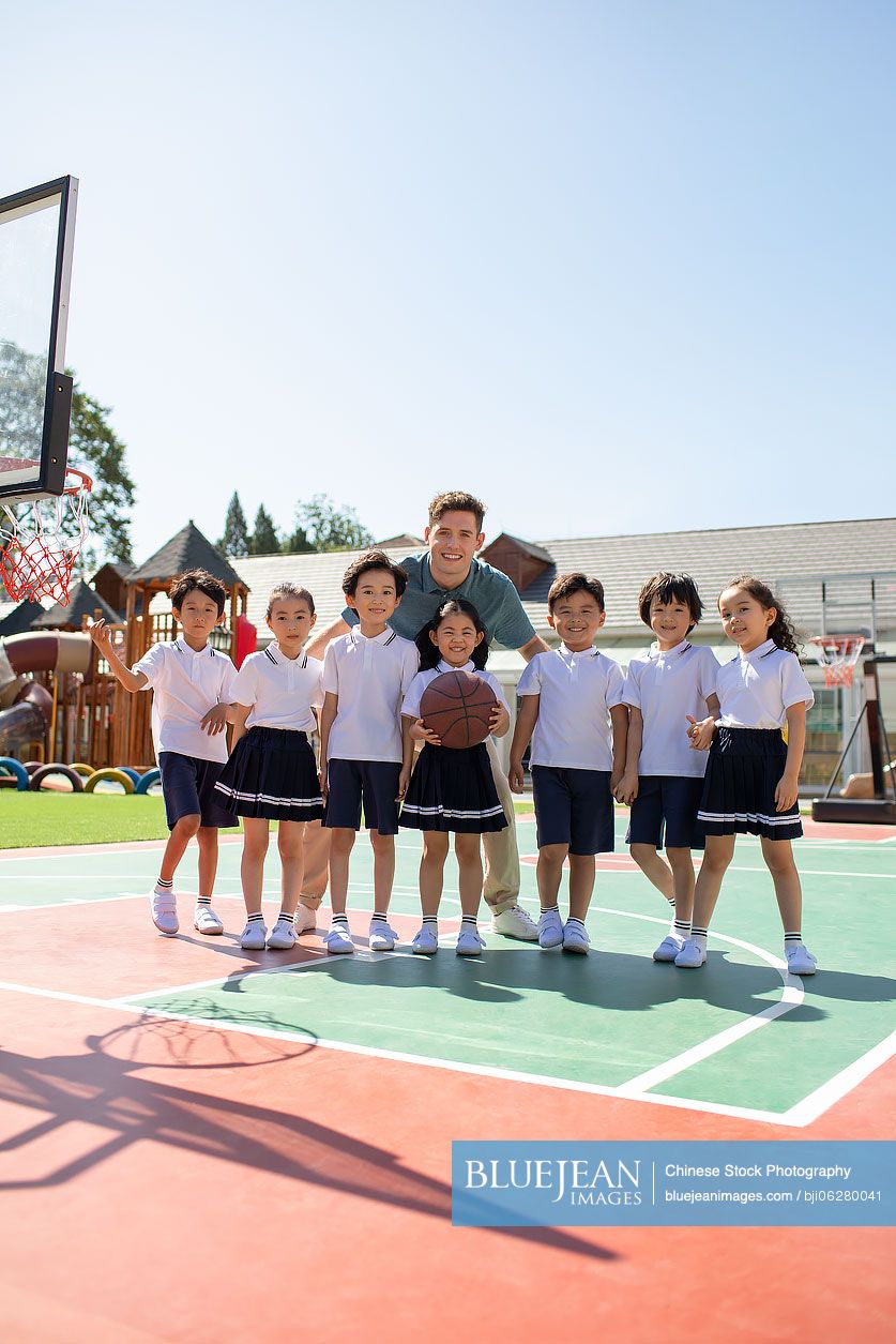 Foreign teacher and children playing basketball in playground