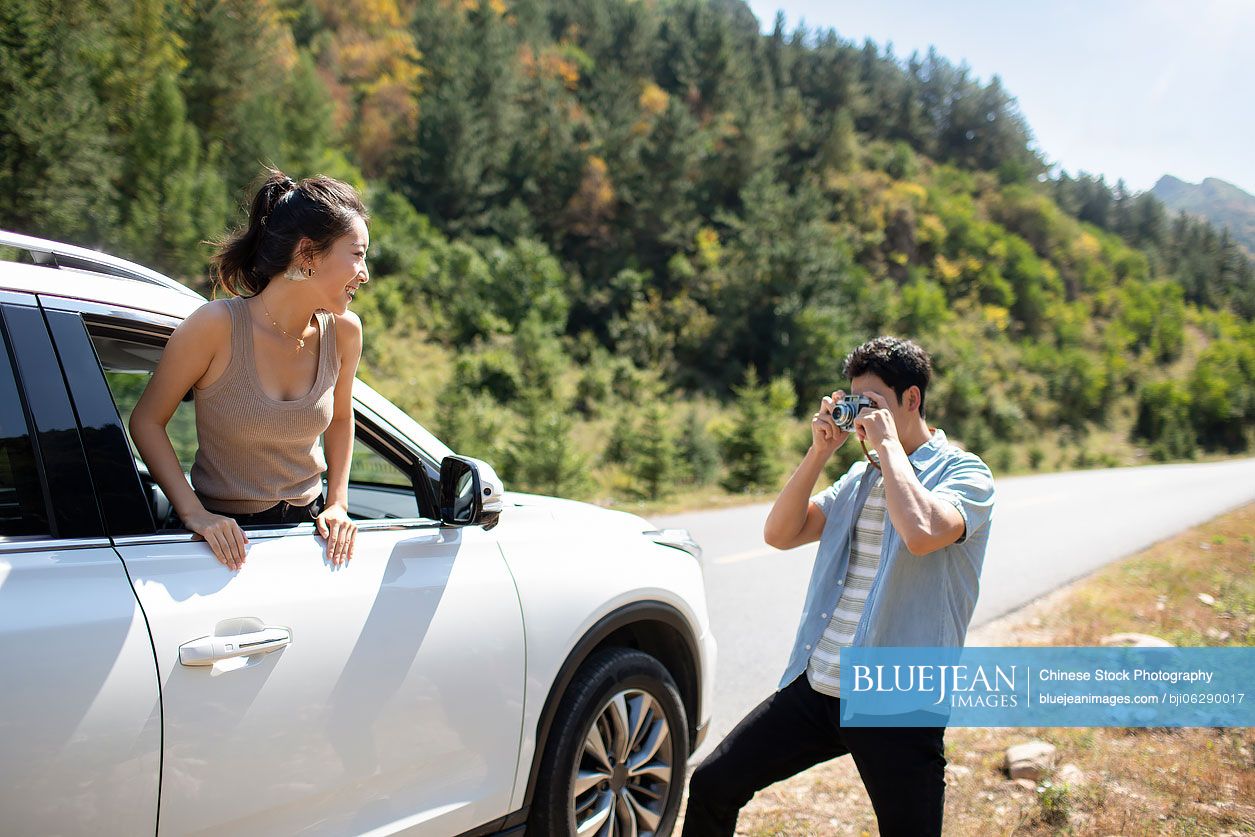 Happy young Chinese couple enjoying road trip