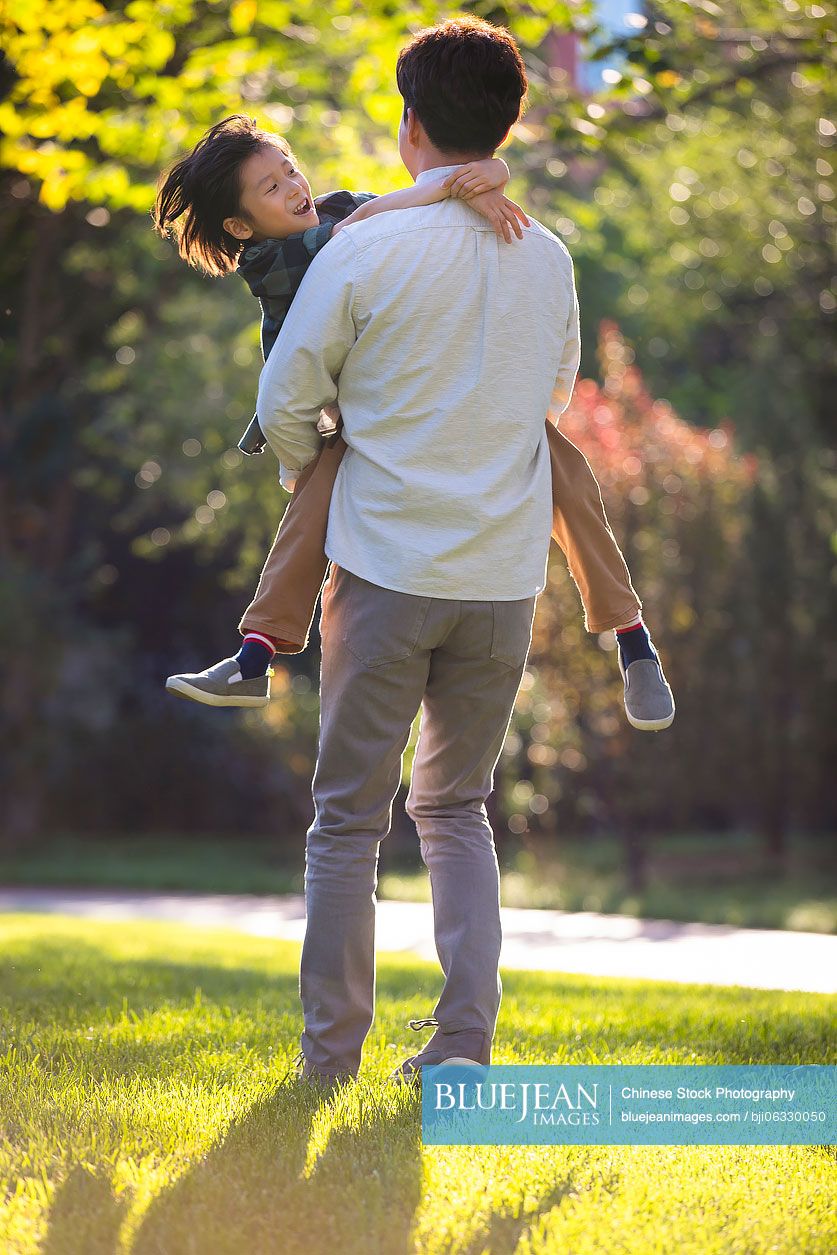 Happy Chinese father and son playing in park