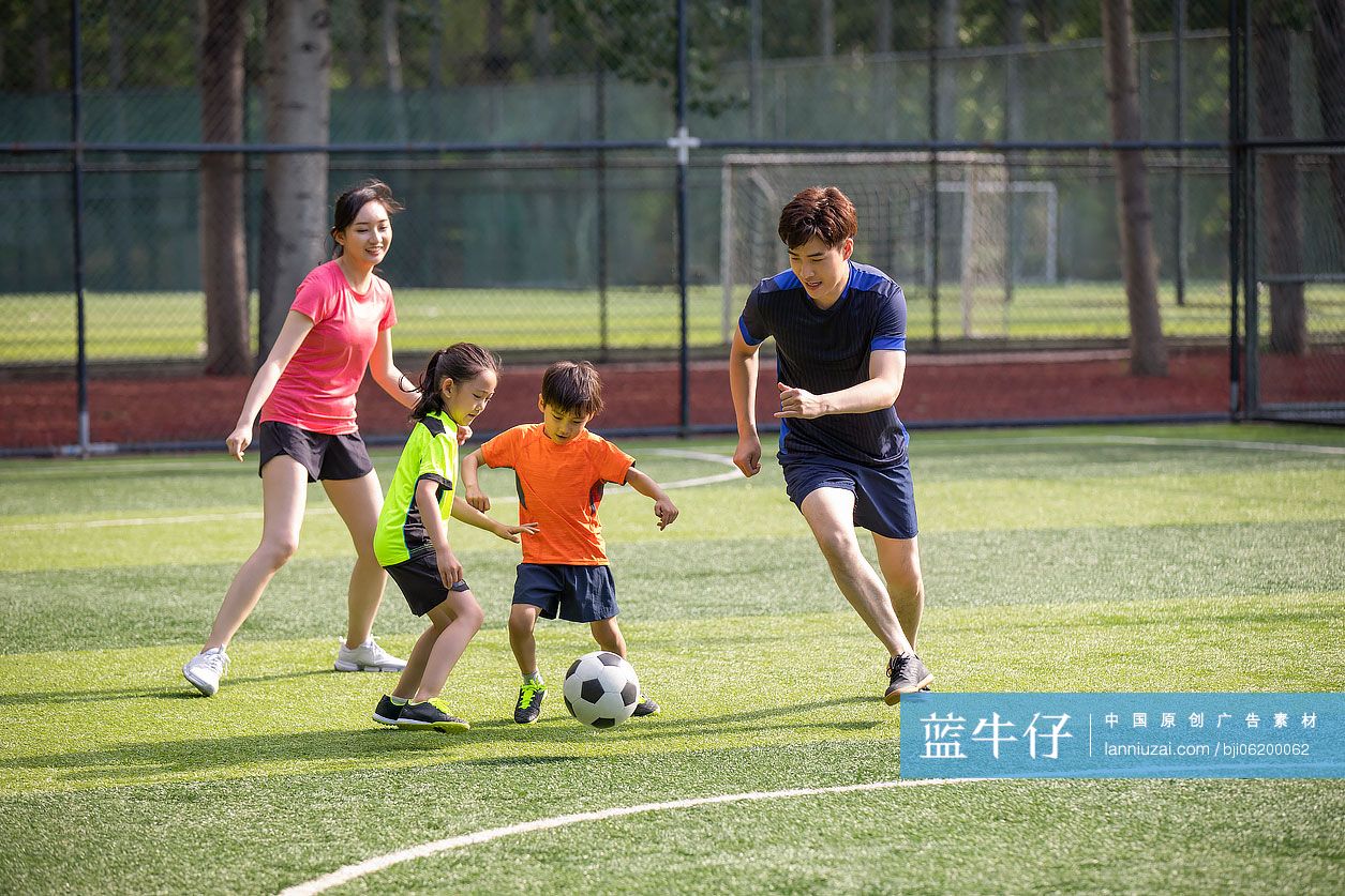 快乐的年轻家庭在足球场踢足球