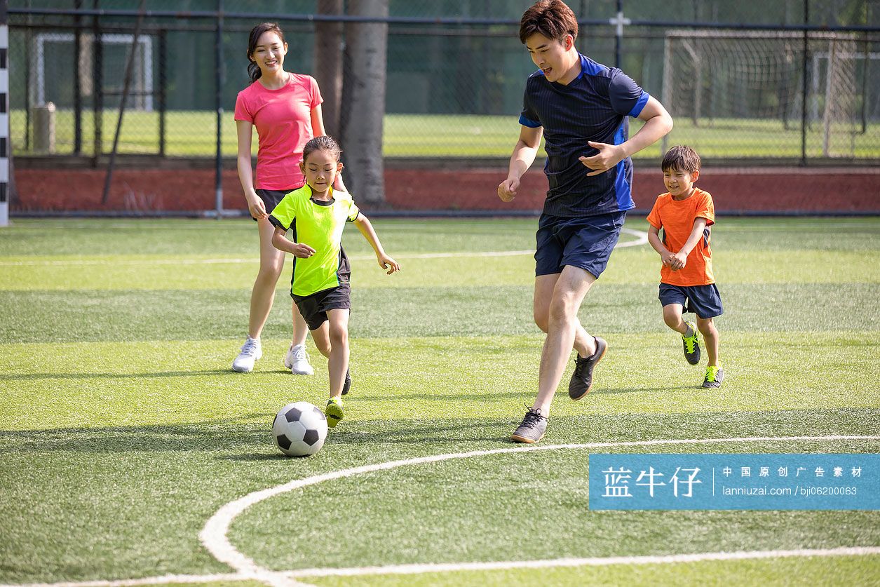 快乐的年轻家庭在足球场踢足球