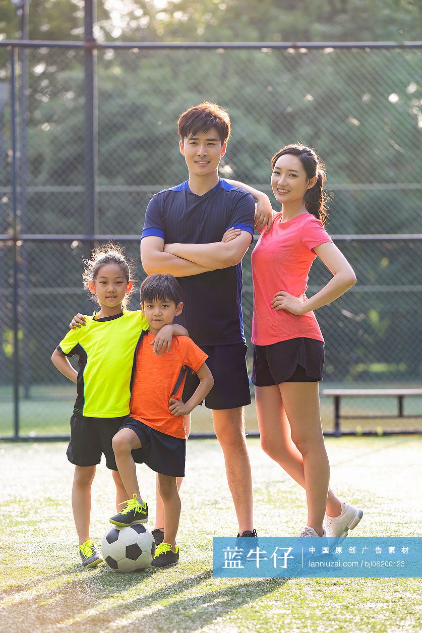 快乐的年轻家庭在足球场踢足球