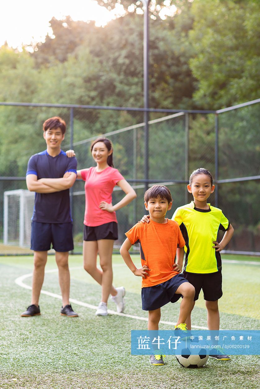 快乐的年轻家庭在足球场踢足球