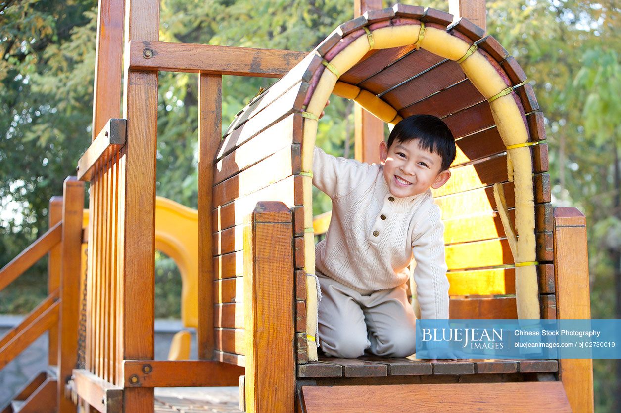 Chinese boy crawling through tunnel in playground