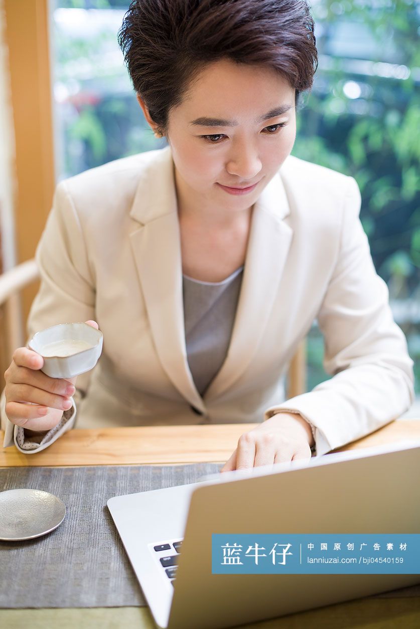 商务女性在茶馆使用笔记本电脑工作