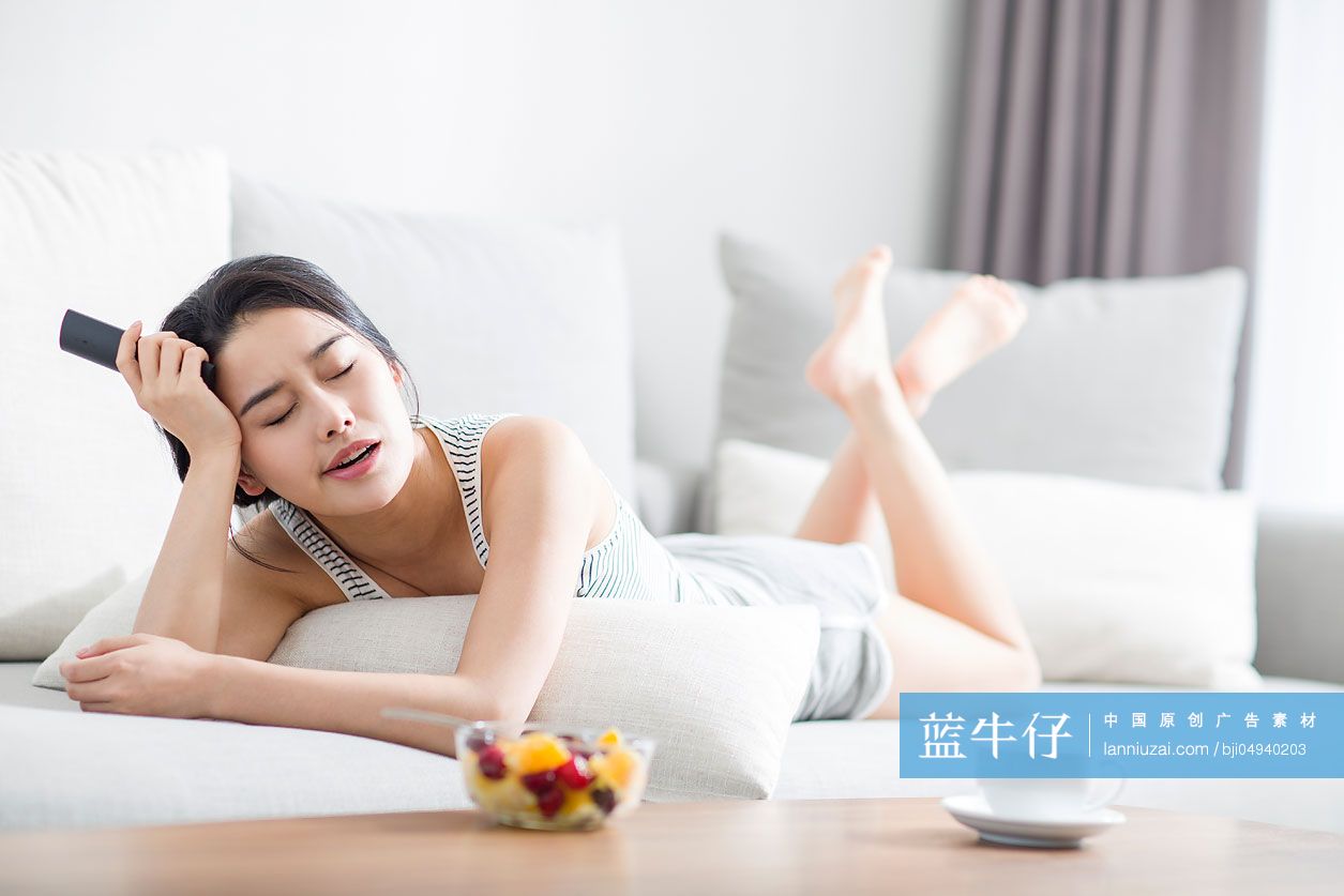 年轻女子在沙发上看电视