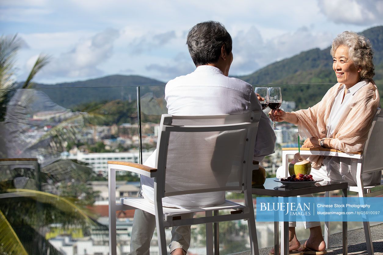 Happy senior Chinese couple relaxing on balcony
