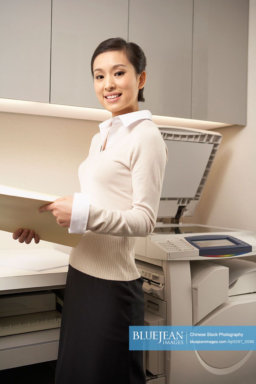 Chinese Young Woman Standing Next To Photocopier