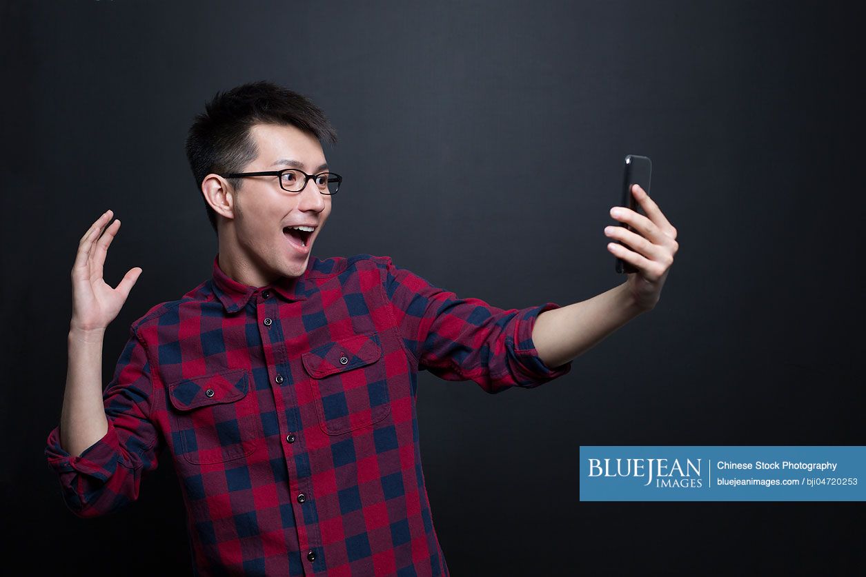 Excited Chinese man holding a smart phone