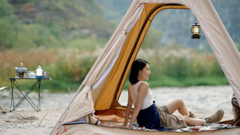 Cheerful young Chinese woman looking out from tent