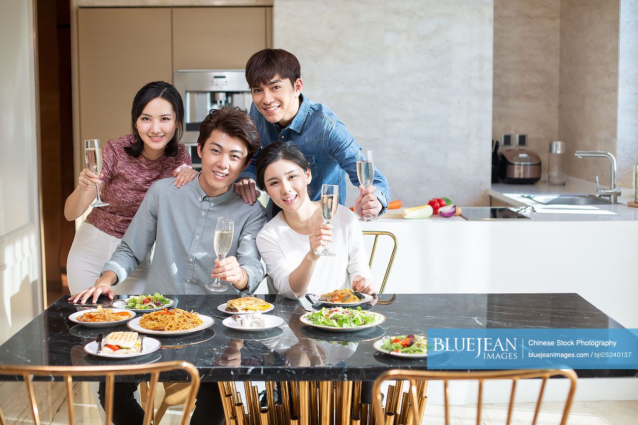 Young Chinese friends toasting at home