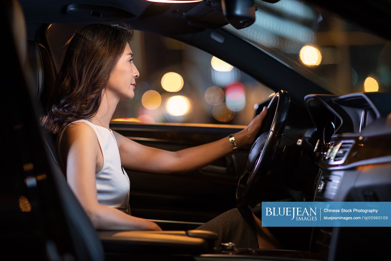 Confident Chinese businesswoman driving car