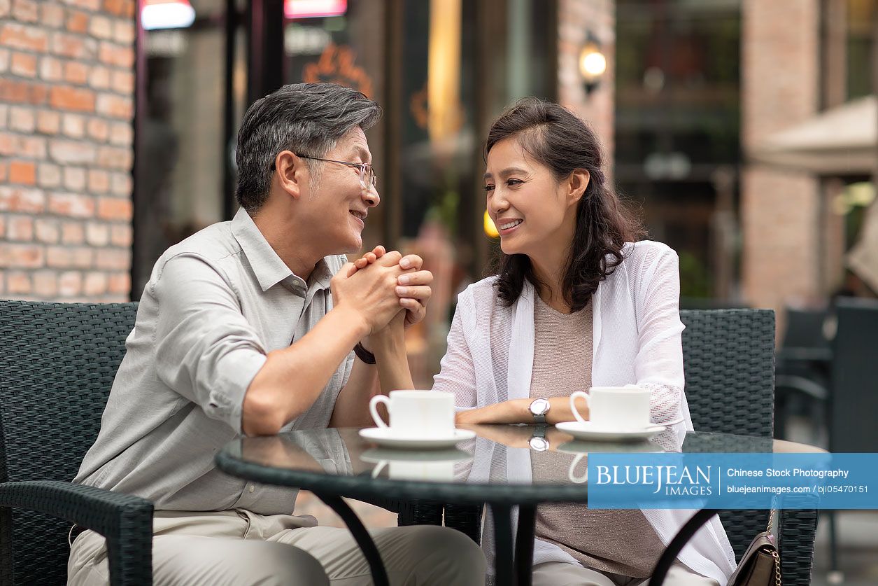 Mature Chinese couple drinking coffee in coffee shop