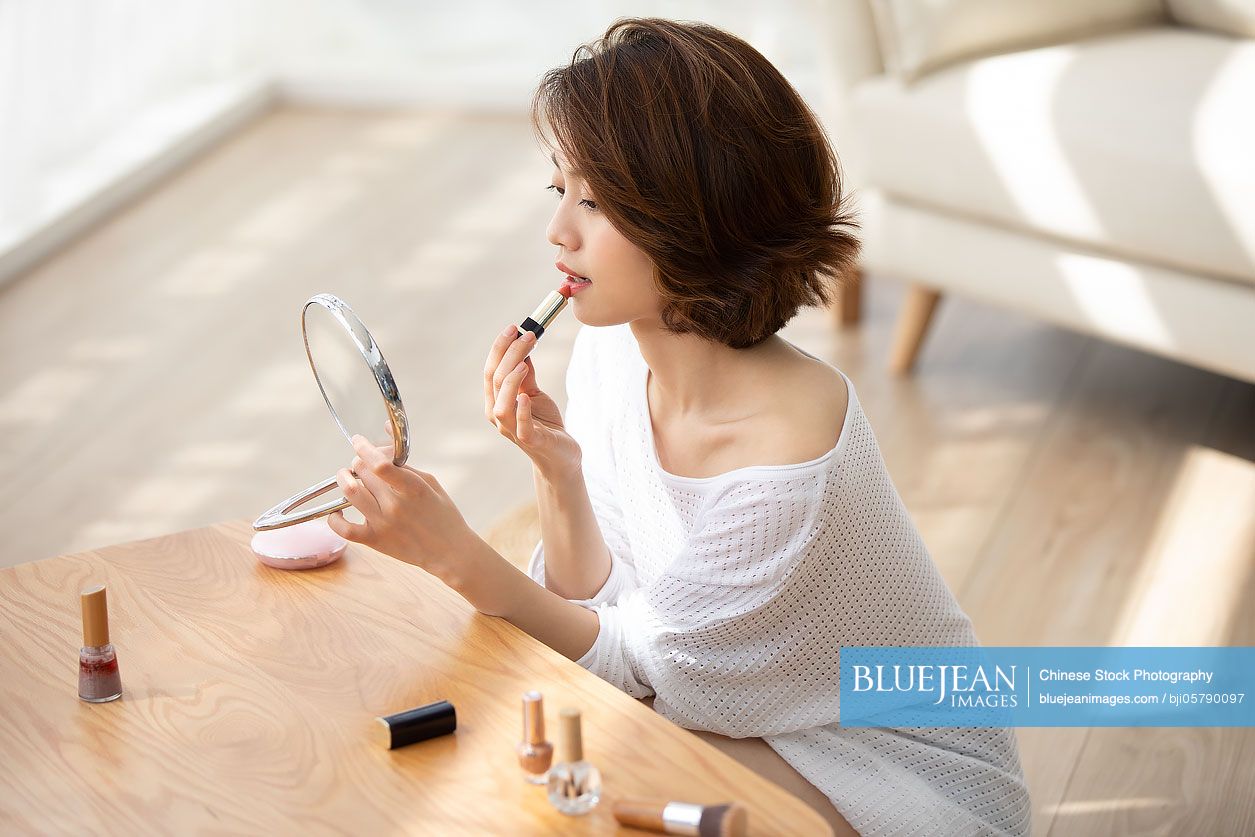 Young Chinese woman applying makeup at home