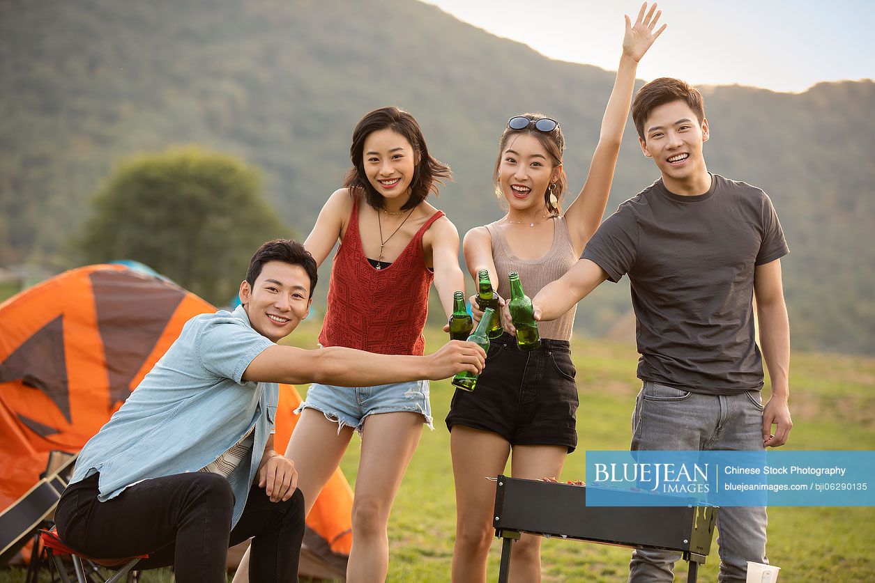 Happy young Chinese friends barbecuing outdoors