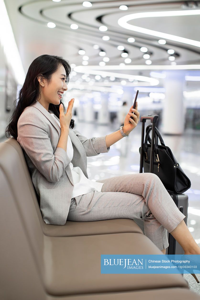 Young Chinese businesswoman using smartphone in airport