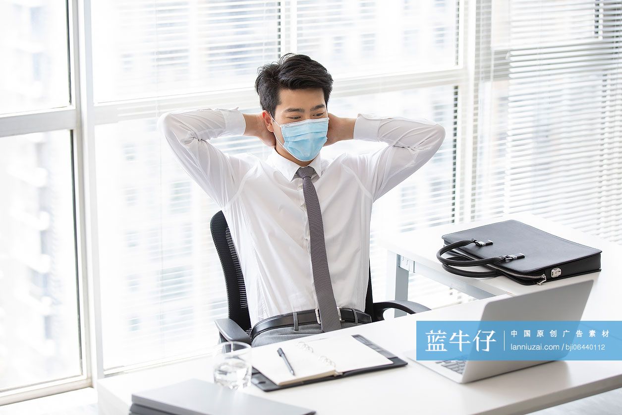 年轻的商务男士戴着口罩工作