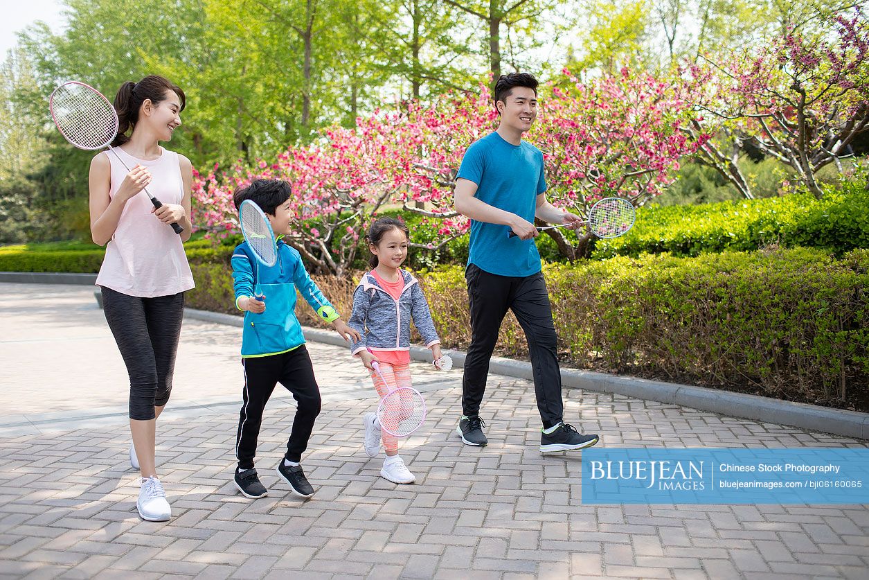 Happy young Chinese family playing badminton in park