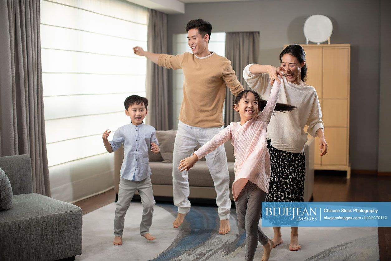 Happy young Chinese family having fun in living room