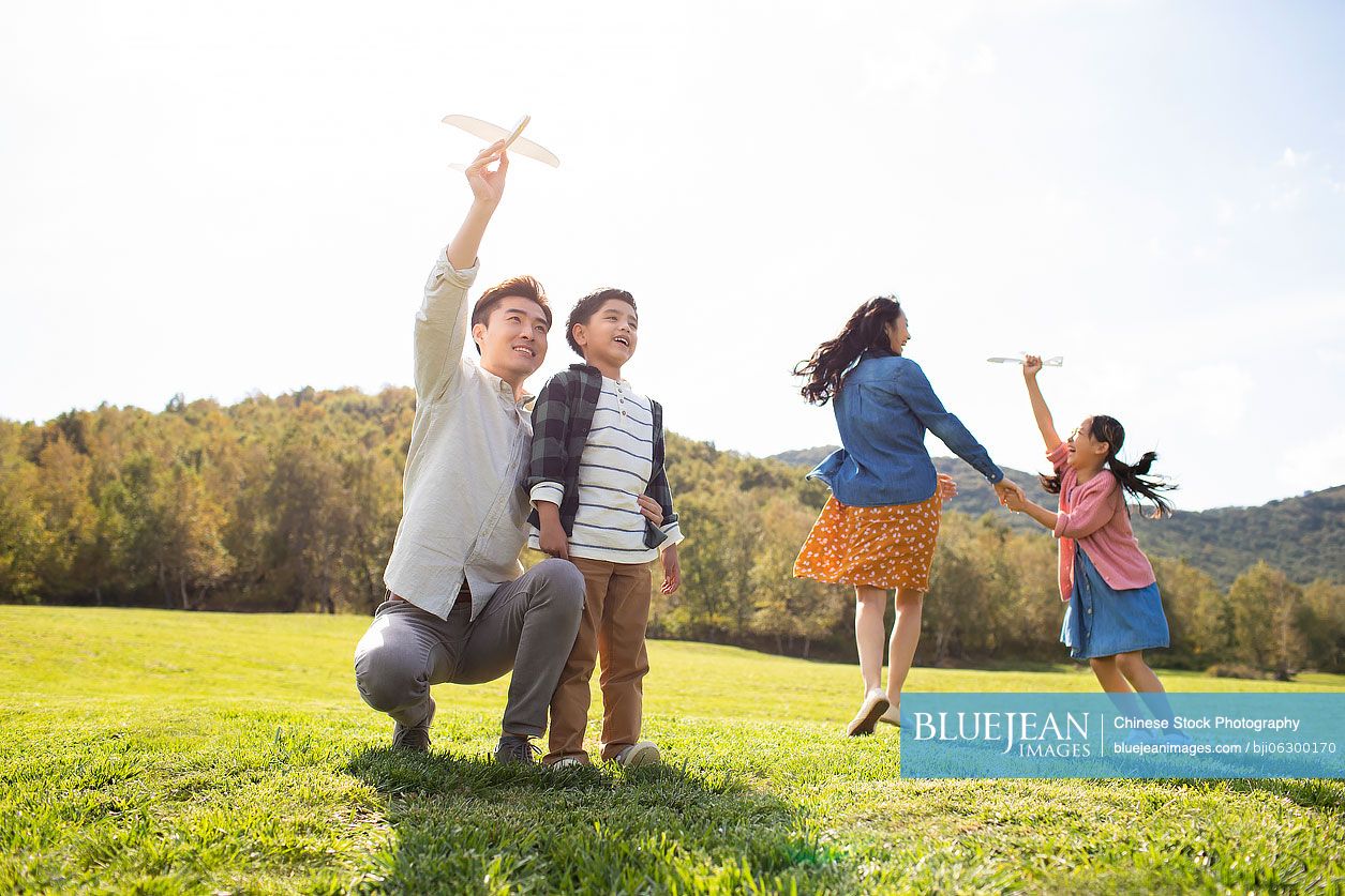 Happy young Chinese family playing on meadow