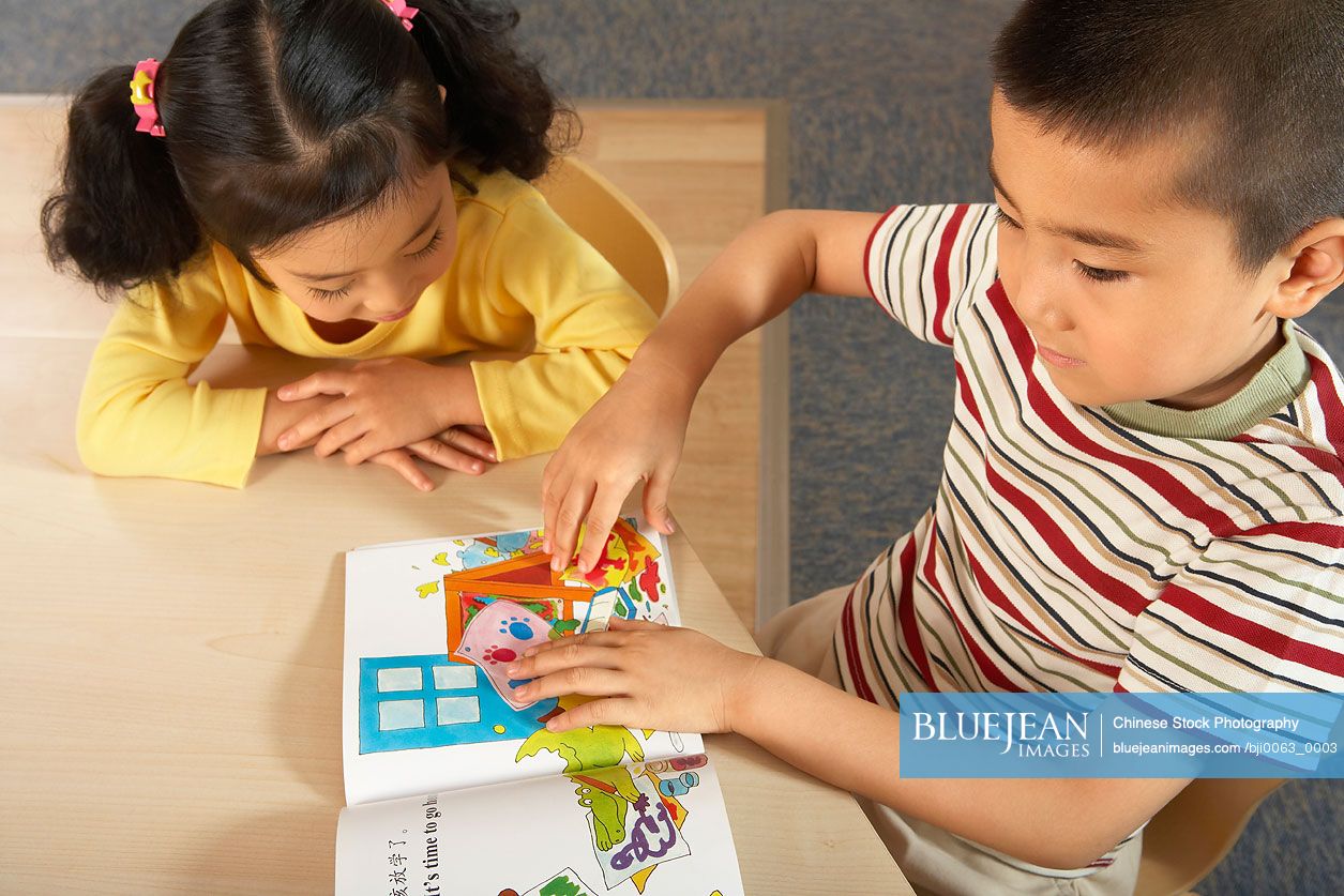 Young Chinese Children Reading A Book