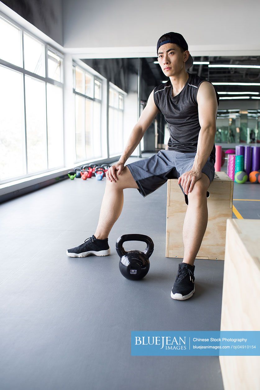 Young Chinese man sitting at gym