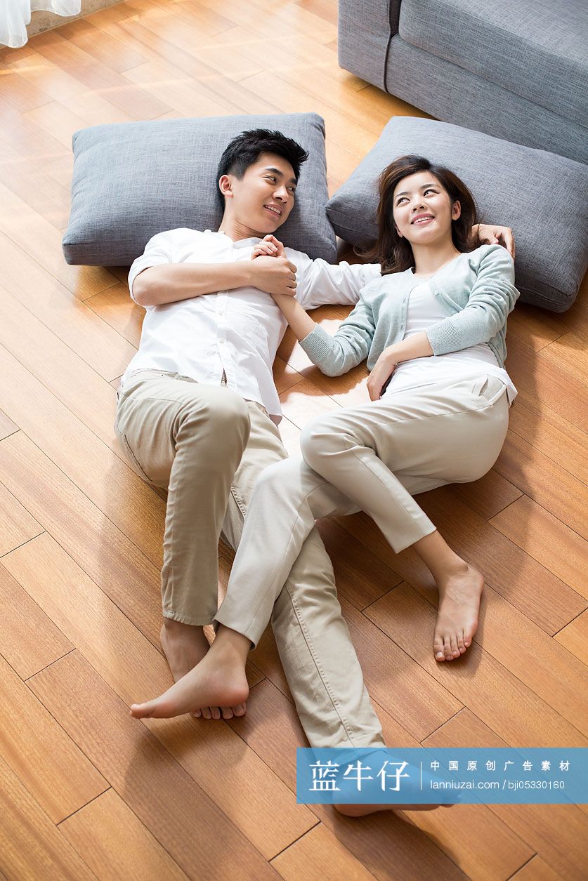 年轻夫妇躺在木地板上休息