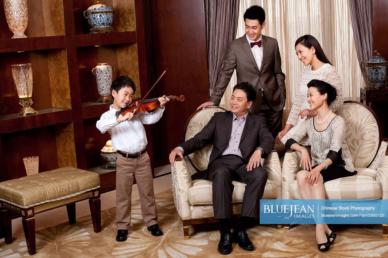 Little Chinese boy playing violin in front of family members