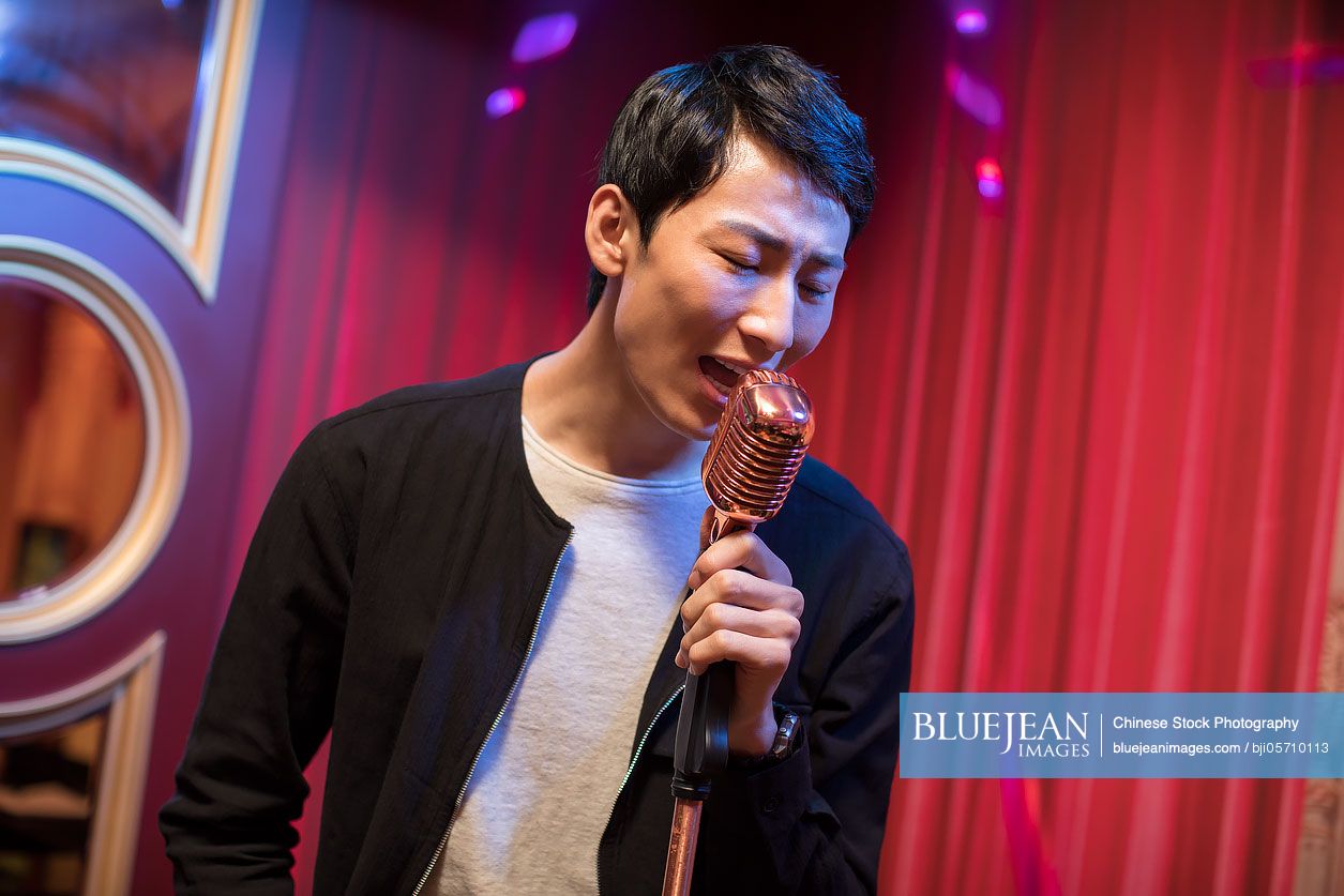 Young Chinese man singing karaoke in nightclub