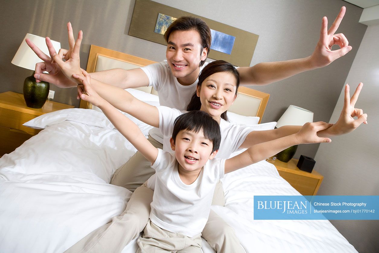 Portrait of a young Chinese family on a bed