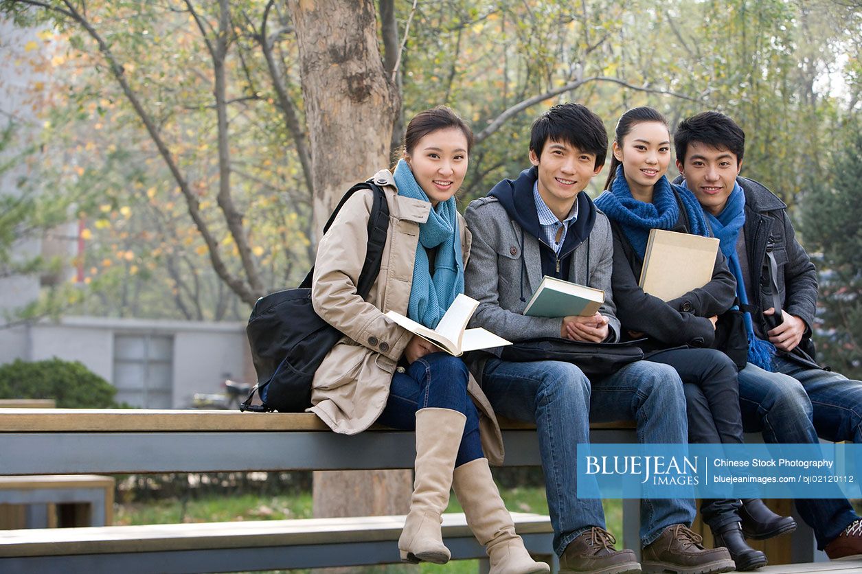 A group of Chinese college students sitting on a park bench