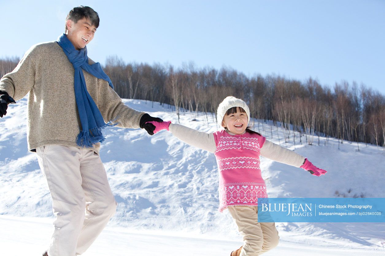 Chinese father playing with daughter in snow