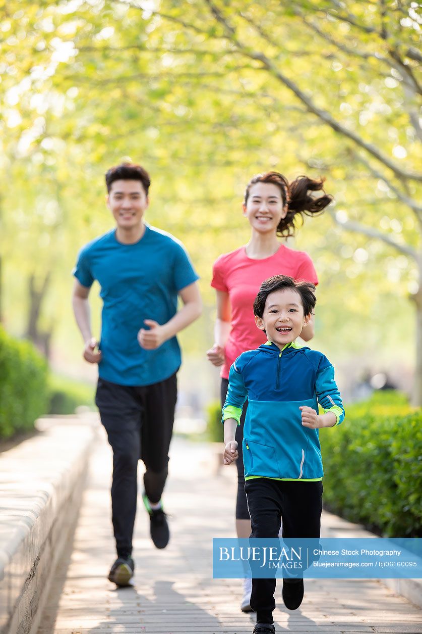 Happy young Chinese family running in park