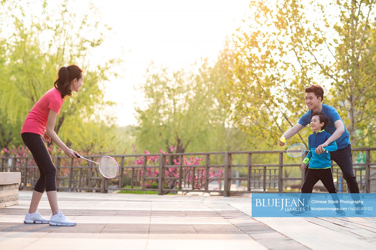 Happy young Chinese family playing badminton in park