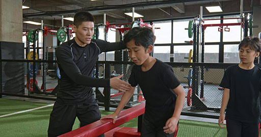 Active Chinese children having exercise class with their coach in gym,4K