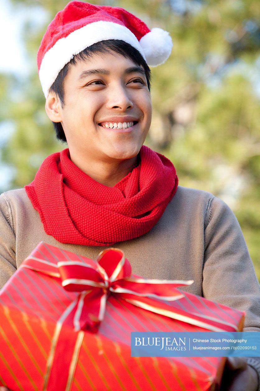 Young Chinese man holding Christmas present